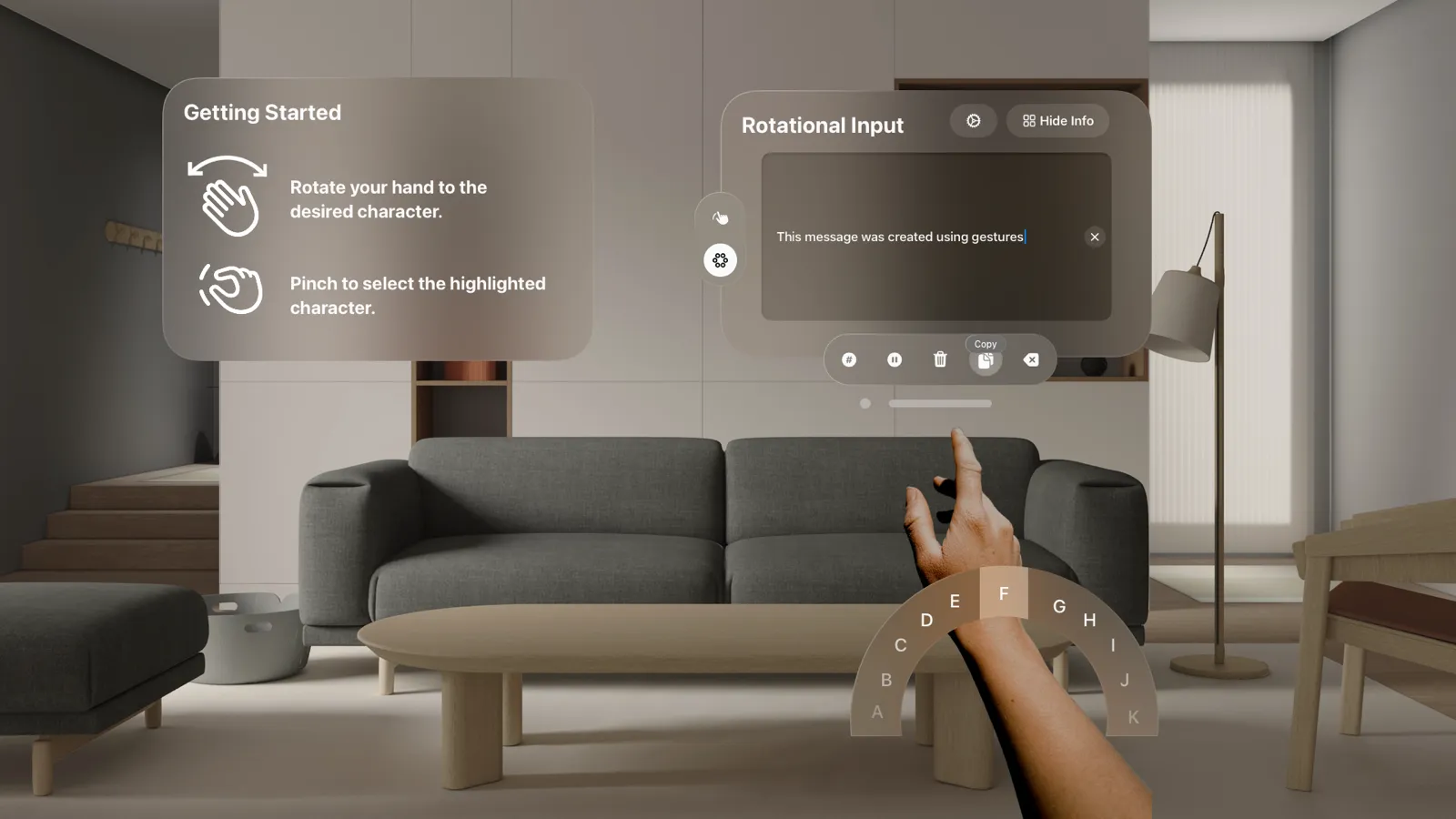 Rotational input in visionOS: a semicircle of letters follows the user’s raised hand in a living room, next to a Getting Started panel and a text field.